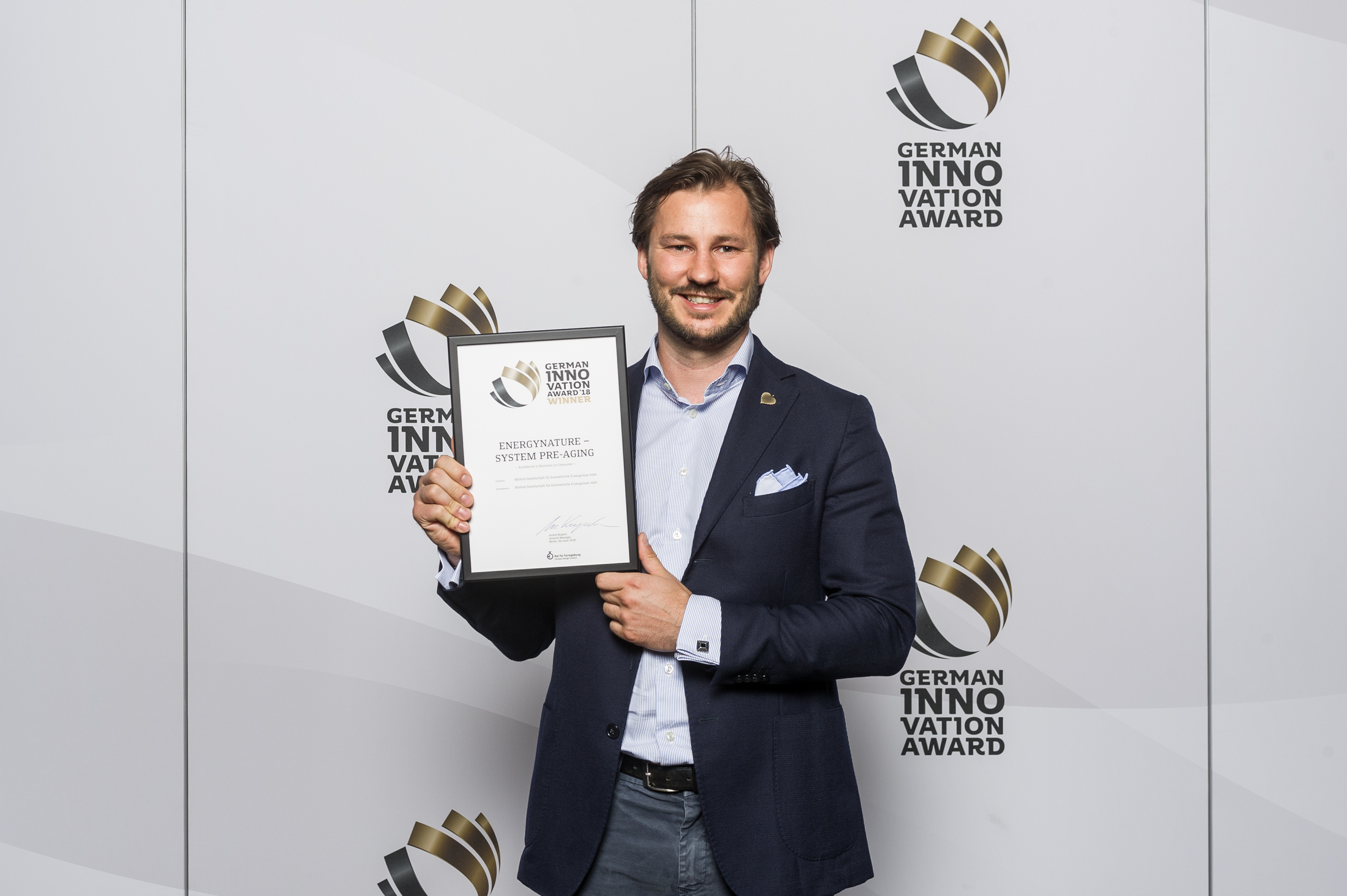 Mann in Anzug hält Urkunde für German Innovation Award Winner 2018 mit Text EnergyNature – System Pre-Aging