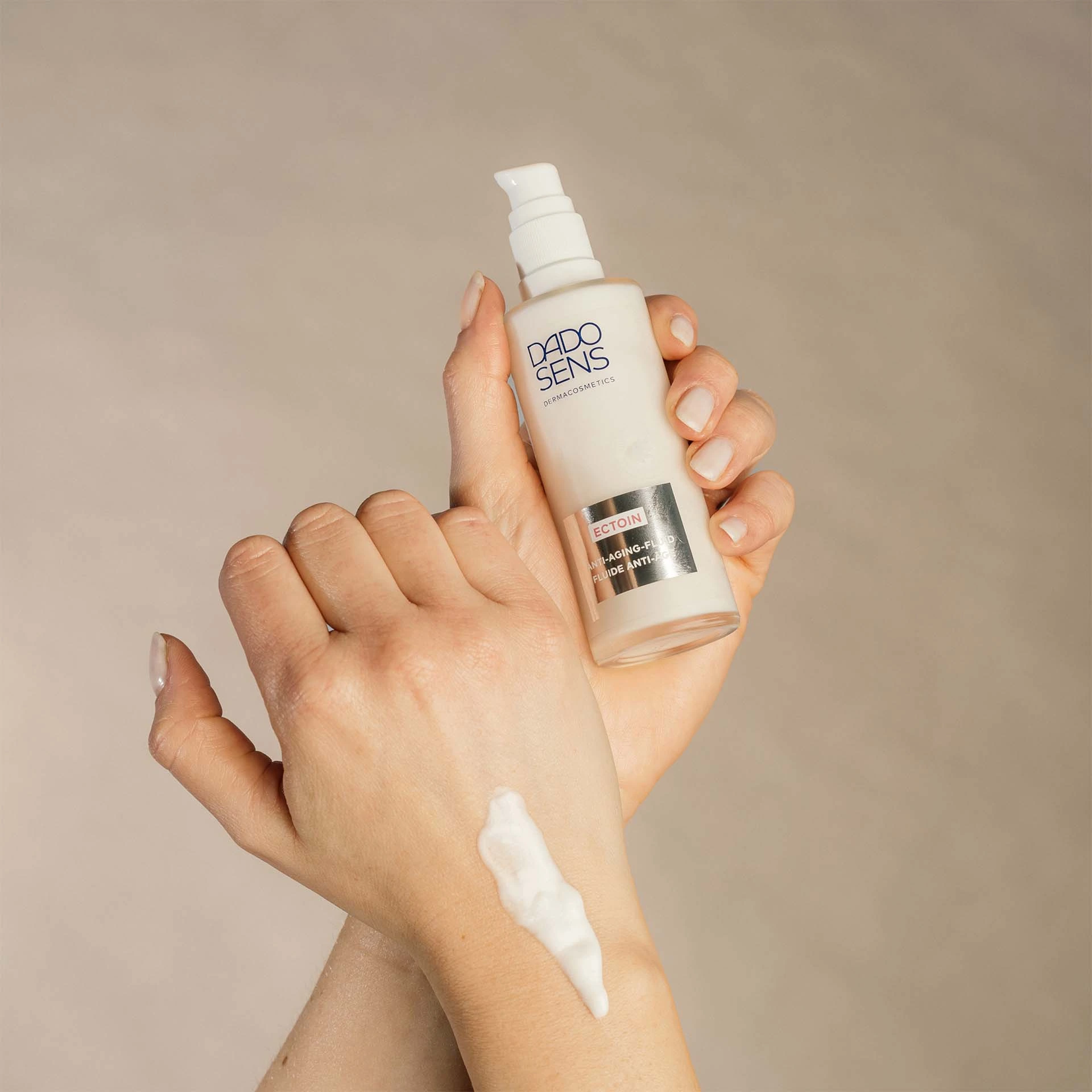 DADO SENS ECTOIN Anti-Aging-Fluid in Hand gehalten, weiße Creme auf Handrücken aufgetragen