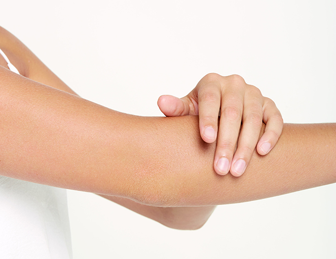Hand berührt den ausgestreckten Unterarm einer Person vor weißem Hintergrund, Fokus auf Haut und Gelenk