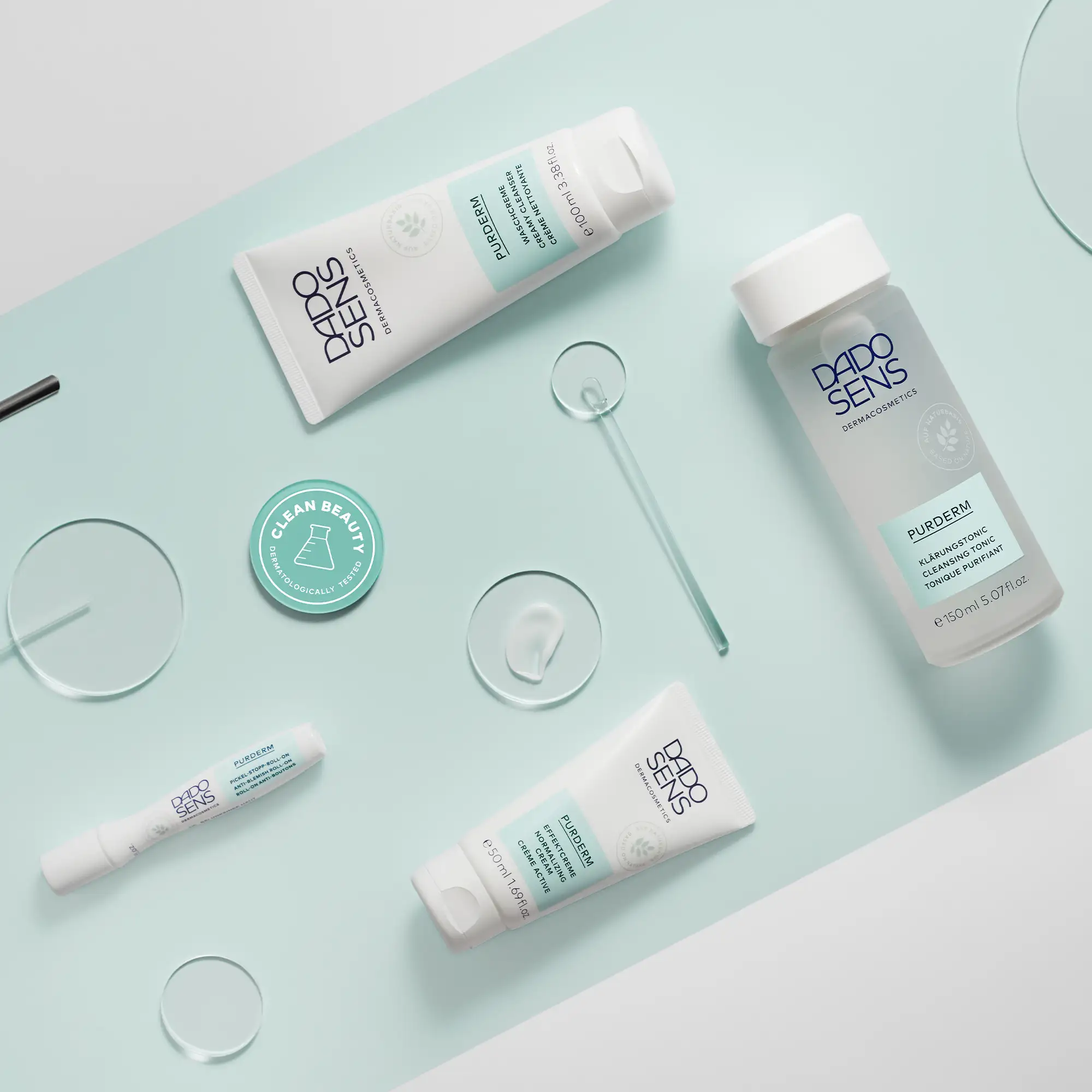 DADO SENS PURDERM Serie mit Waschcreme, Klärungstonic, Effektcreme und Pickel-Stopp-Roll-on auf hellblauem Hintergrund