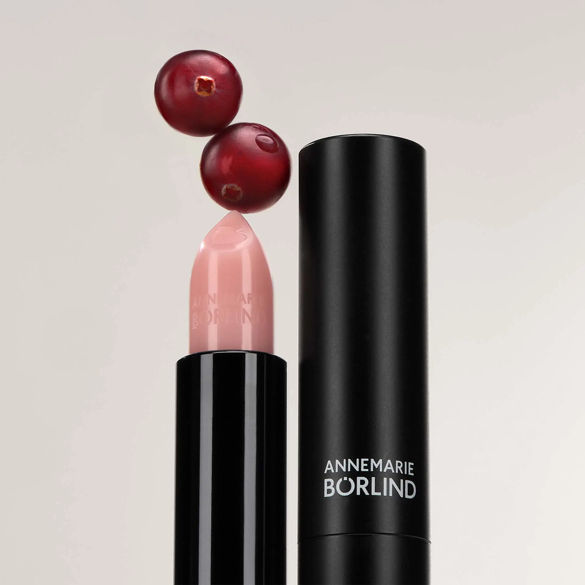 ANNEMARIE BÖRLIND Lippenstift in hellem Rosé mit Herzprägung auf der Spitze und schwarzer Hülse mit Cranberrys, dem Wirkstoff im Produkt