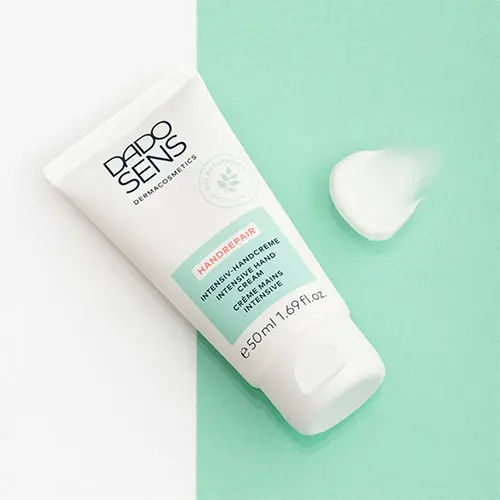 DADO SENS Intensiv-Handcreme HANDREPAIR 50 ml auf zweifarbigem Untergrund mit Cremeprobe