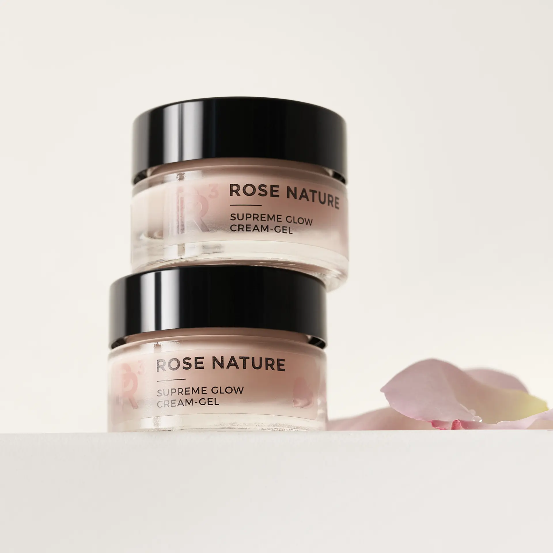 ROSE NATURE Supreme Glow Cream-Gel im 15-ml-Glas, zwei Dosen gestapelt, Rosenblütenblatt daneben