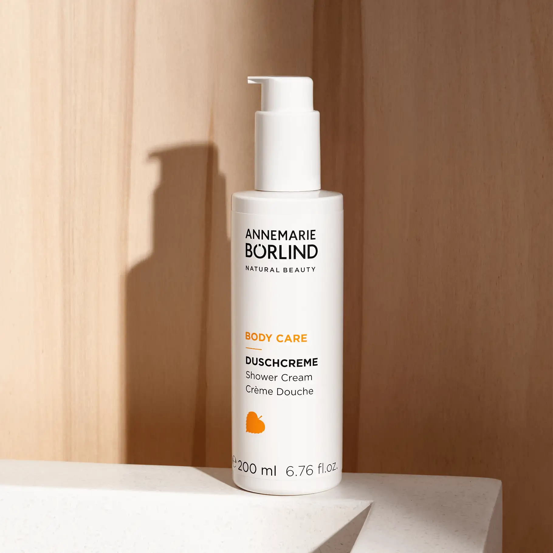 ANNEMARIE BÖRLIND BODY CARE Duschcreme im weißen Spender, 200 ml, vor hellem Holz und Steinoberfläche
