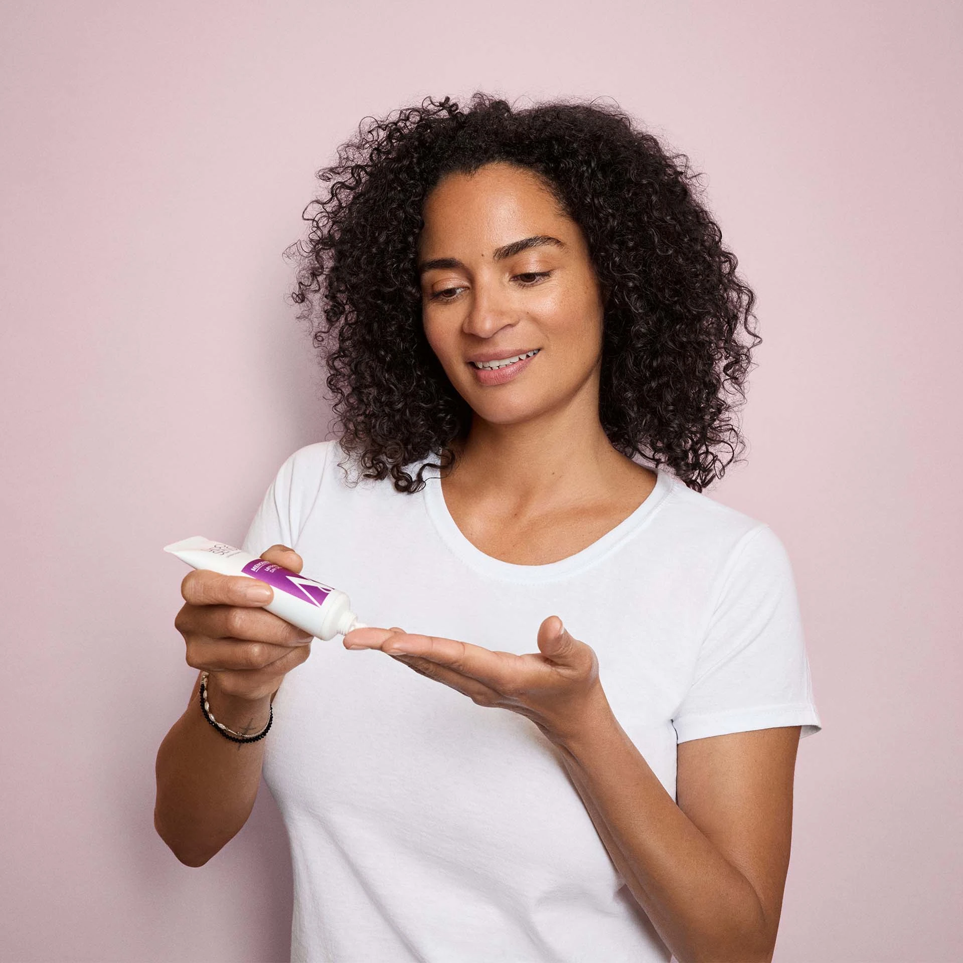 Frau trägt DADO SENS MENOENERGY Cleanser auf Hand auf vor rosa Hintergrund