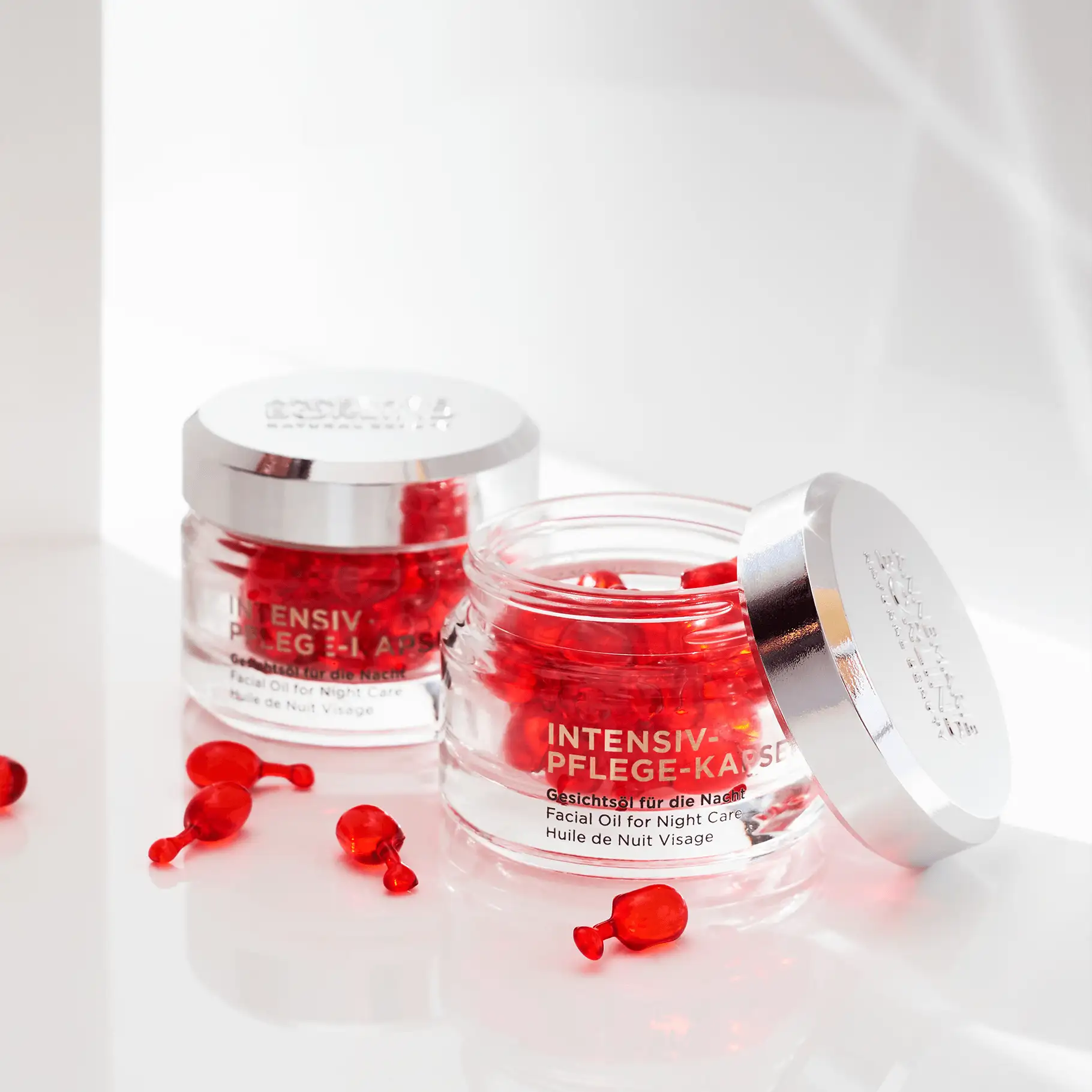 ANNEMARIE BÖRLIND Intensiv-Pflege-Kapseln mit rotem Gesichtsöl, zwei Gläser, eines offen, auf weißem Untergrund