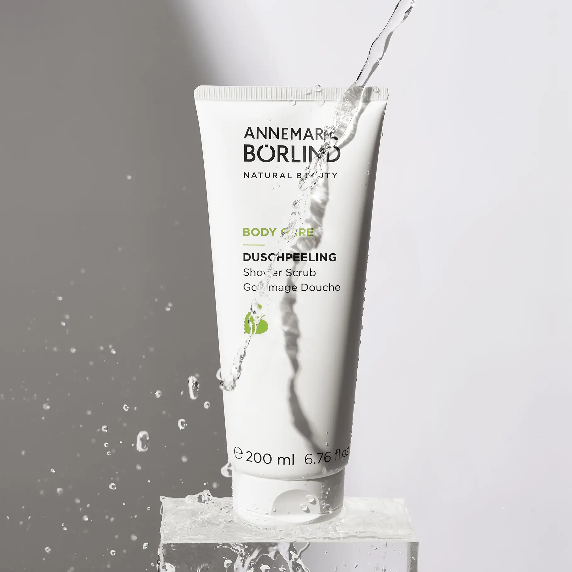 ANNEMARIE BÖRLIND Body Care Duschpeeling in weißer Tube mit Wasserstrahl und Wassertropfen