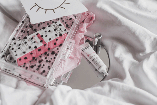 ANNEMARIE BÖRLIND Sensitive Care Creme und Serum auf Spiegel mit transparentem Kosmetikbeutel und rosa Stoff auf weißem Bett