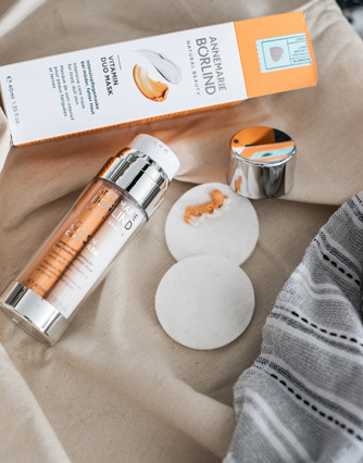 ANNEMARIE BÖRLIND Vital Mask Ultra mit Verpackung, Spenderflasche, geöffnetem Deckel und zwei Wattepads auf beige Stoff