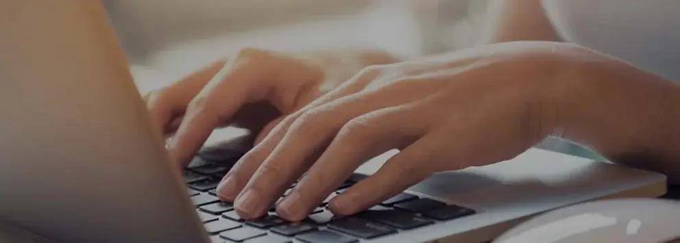 Hände tippen auf Laptop-Tastatur, Fokus auf Arbeit am Computer in heller Umgebung