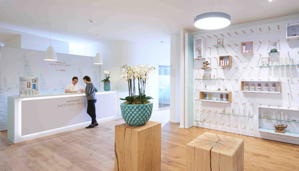 Empfangsbereich mit Beratungsgespräch, blauer Orchideentopf auf Holzsäule und Produktwand im NATURAL BEAUTY SPA