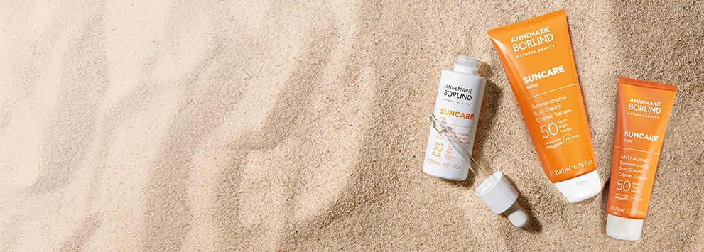 ANNEMARIE BÖRLIND SUNCARE Sonnencremes mit LSF 30 und 50 in verschiedenen Größen auf Sandfläche