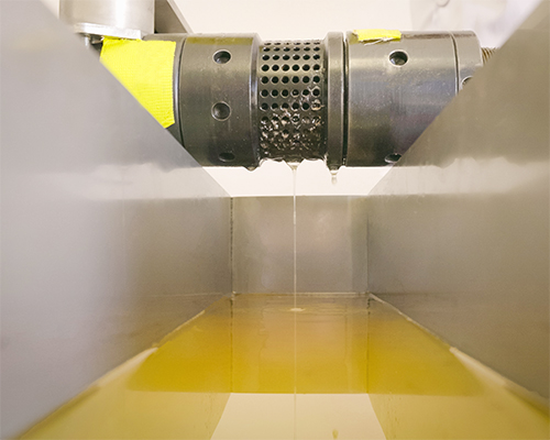 Jojobaöl tropft aus einer Metallpresse in eine Auffangwanne während der Produktion