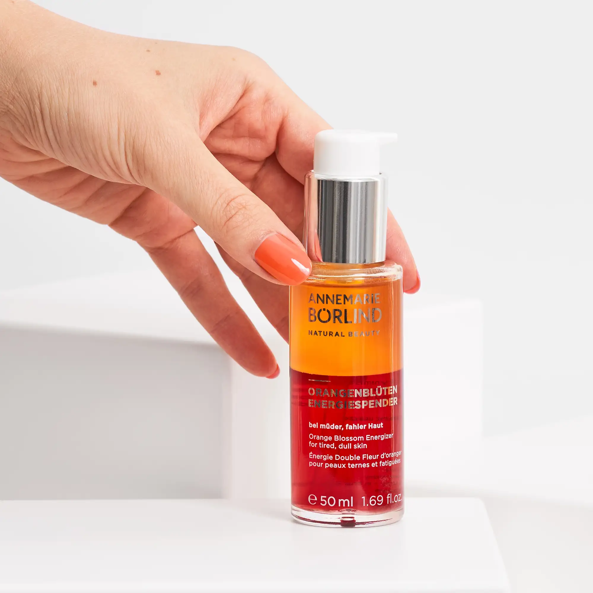 Hand hält ANNEMARIE BÖRLIND Orangenblüten Energiespender Serum in 50 ml Flasche mit Pumpspender