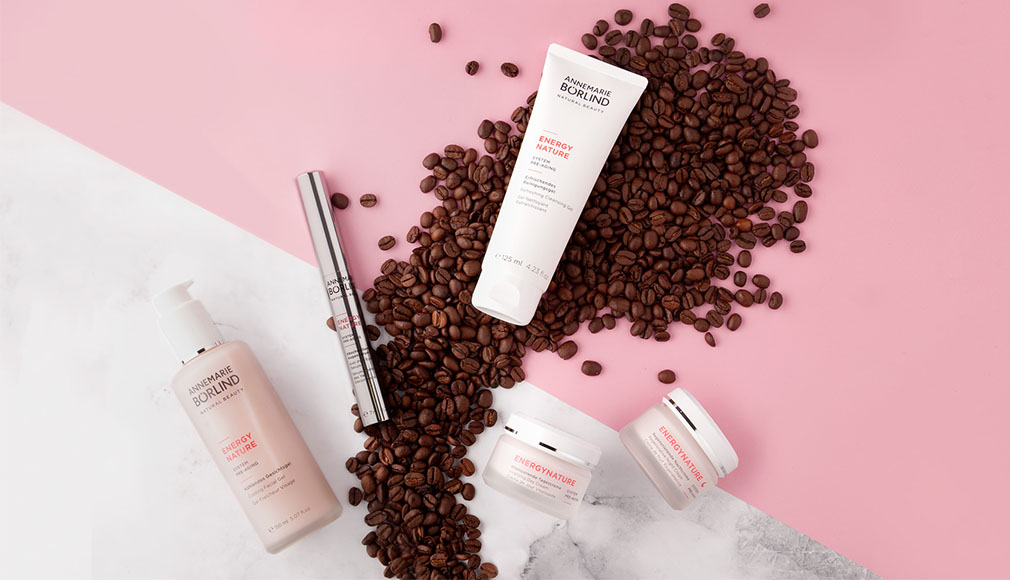 ANNEMARIE BÖRLIND ENERGY NATURE Gesichtspflege mit Koffein, Creme, Serum und Mascara auf rosa-marmoriertem Hintergrund