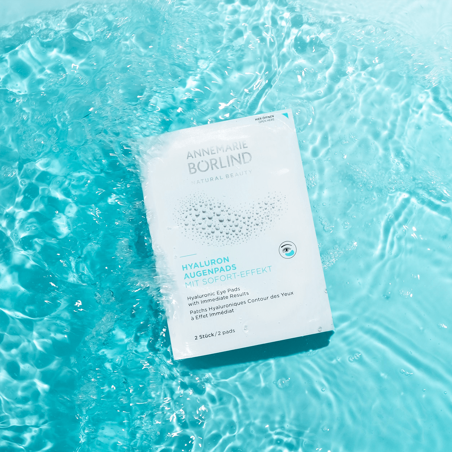 ANNEMARIE BÖRLIND Hyaluron Augenpads mit Sofort-Effekt, weiße Verpackung auf blauem Wasserhintergrund