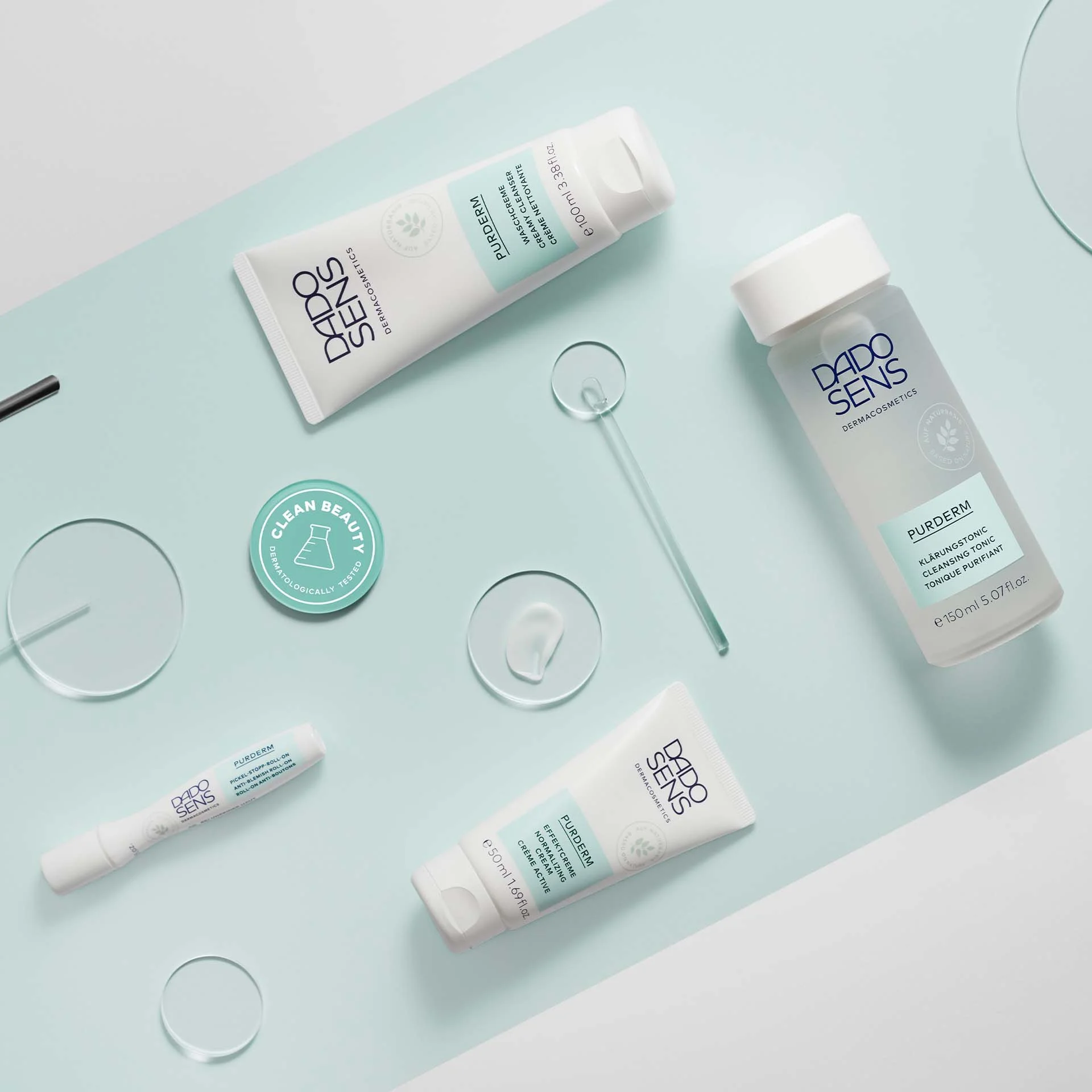 DADO SENS PURDERM Reinigung, Klärungstonic, Effektcreme und Pickel-Stopp-Roll-on auf hellblauem Hintergrund