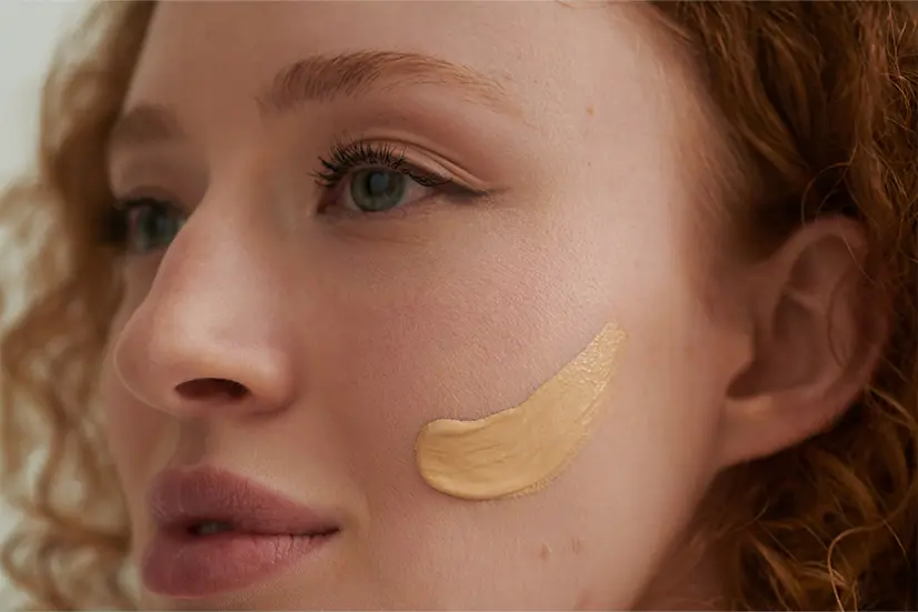 Nahaufnahme einer Frau mit Foundation-Pinselstrich auf der Wange, zeigt Hautstruktur und Make-up-Anwendung