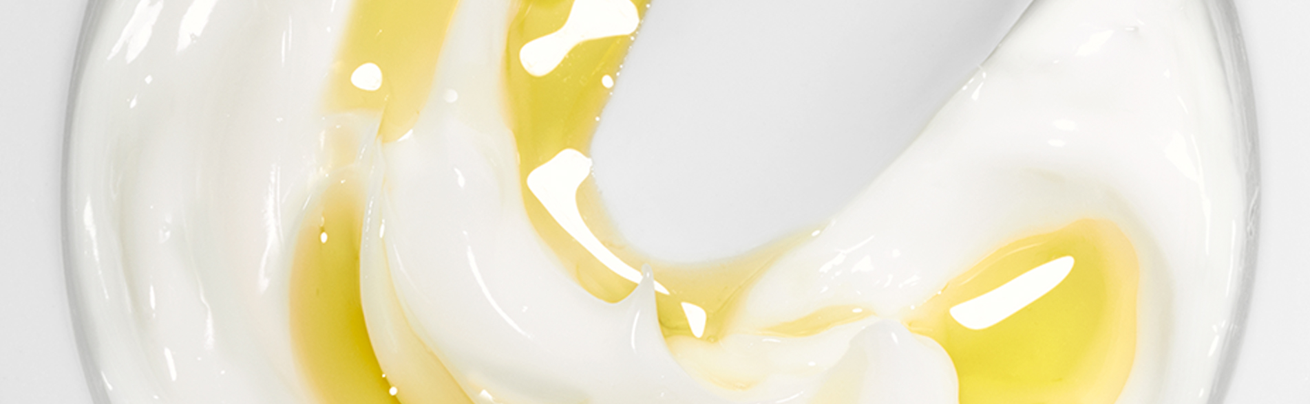 Nahaufnahme einer weißen Creme mit gelben Öltropfen, cremige Textur auf weißem Hintergrund