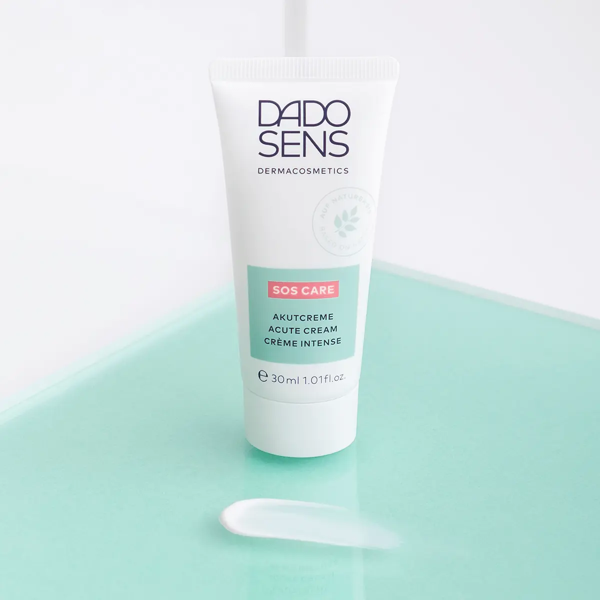 DADO SENS SOS CARE Akutcreme 30 ml Tube mit Cremeprobe auf mintfarbenem Untergrund