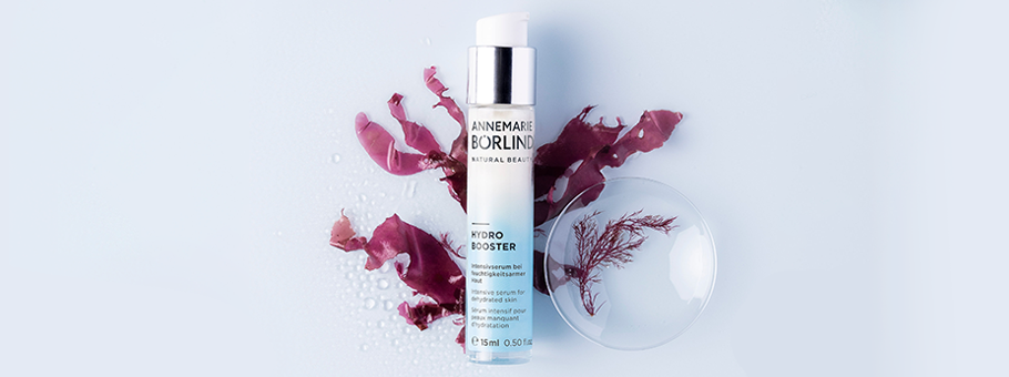 ANNEMARIE BÖRLIND HYDRO BOOSTER Serum mit Rotalge, Flasche vor roter Alge und Wassertropfen auf hellem Hintergrund