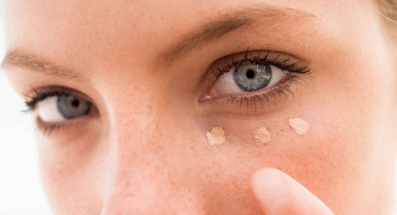 Frau trägt Concealer unter den Augen auf – einfache Tipps, um Augenringe abdecken zu können