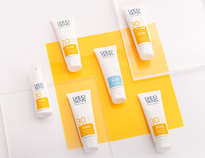 DADO SENS Sonnencremes mit LSF 20 und 30 sowie After-Sun-Pflege auf gelbem Hintergrund
