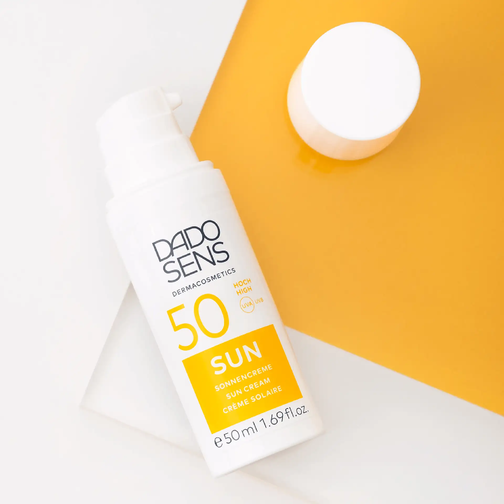 DADO SENS Sun Sonnencreme SPF 50 in geöffneter 50-ml-Tube auf weißem und gelbem Untergrund
