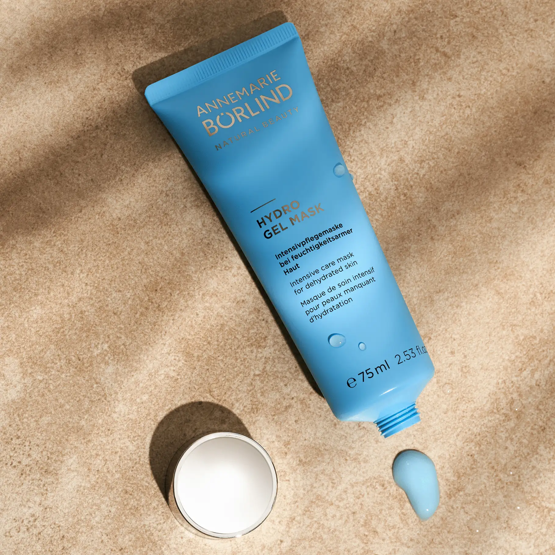 ANNEMARIE BÖRLIND Hydro Gel Mask in blauer Tube mit geöffnetem Deckel und Produktklecks auf sandfarbenem Untergrund