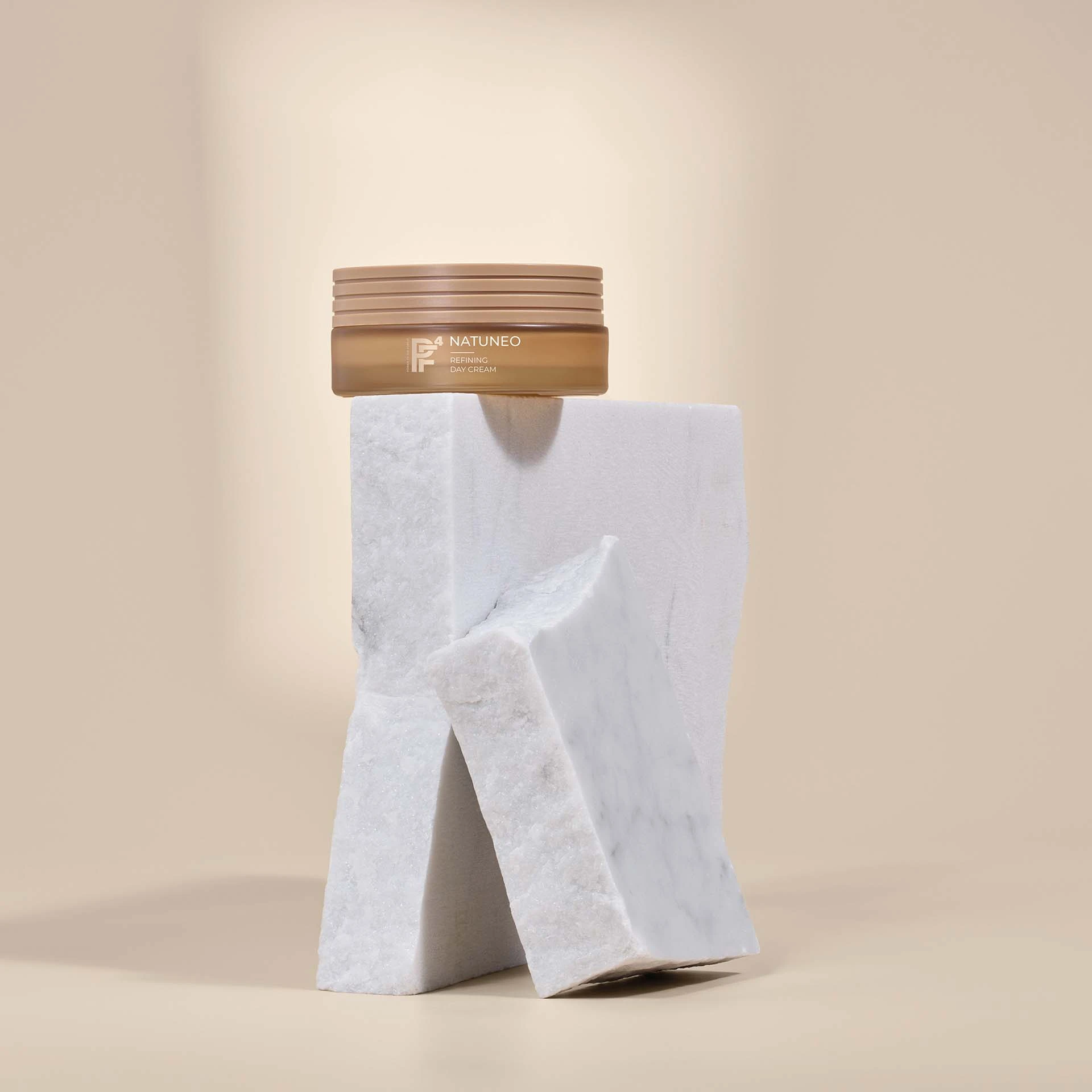 NATUNEO Refining Day Cream in braunem Tiegel auf weißen Marmorsteinen vor beigem Hintergrund