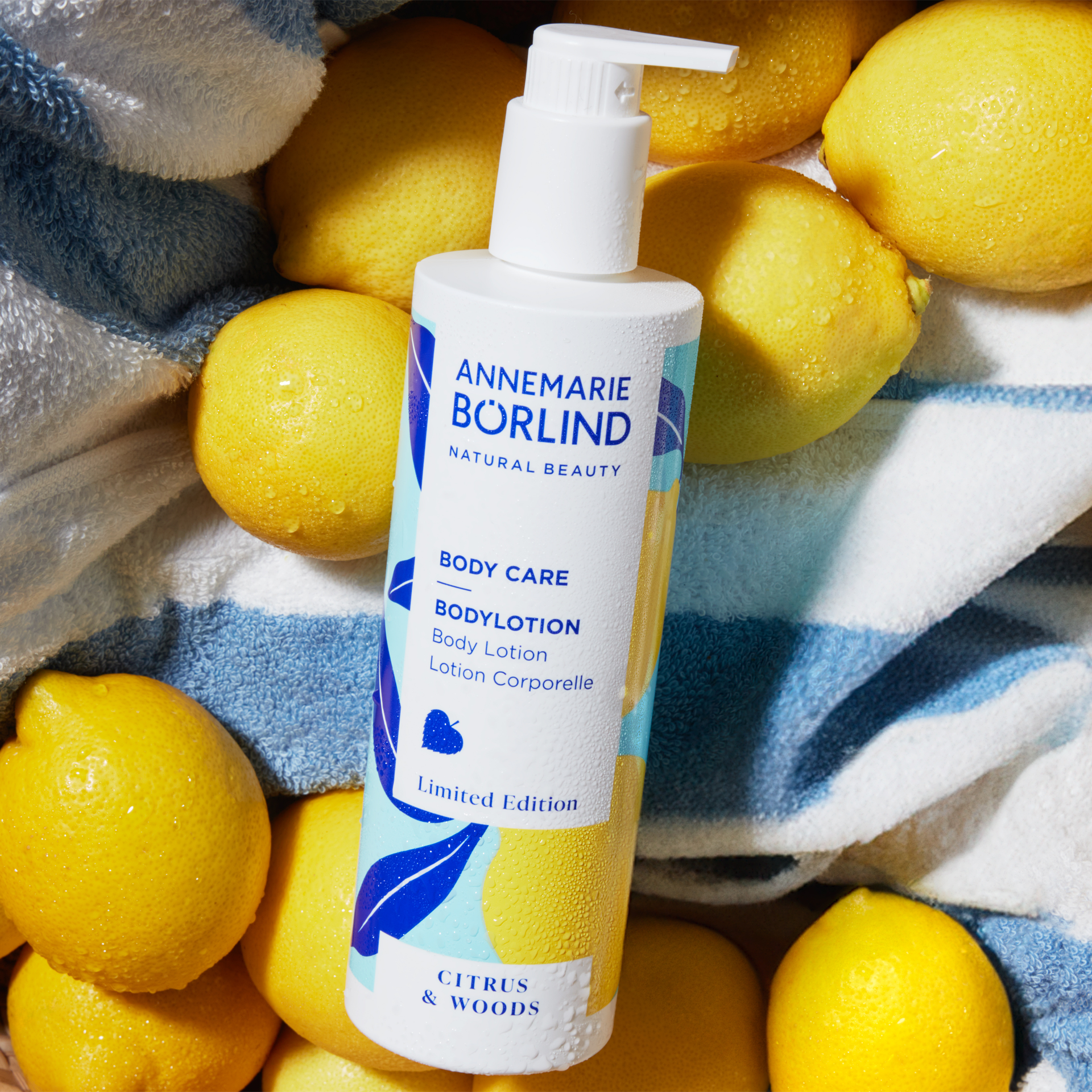 ANNEMARIE BÖRLIND Body Lotion Citrus & Woods, Limited Edition, umgeben von Zitronen auf Handtuch.