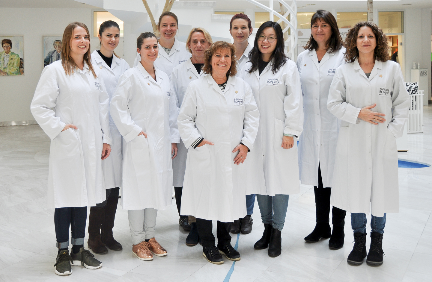 Zehn Frauen in weißen LABORKITTELN mit ANNEMARIE BÖRLIND-Logo stehen in einem hellen Innenraum und lächeln in die Kamera