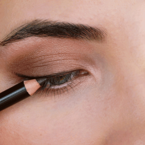 Nahaufnahme eines Auges, das mit einem schwarzen Kajalstift am oberen Wimpernkranz betont wird