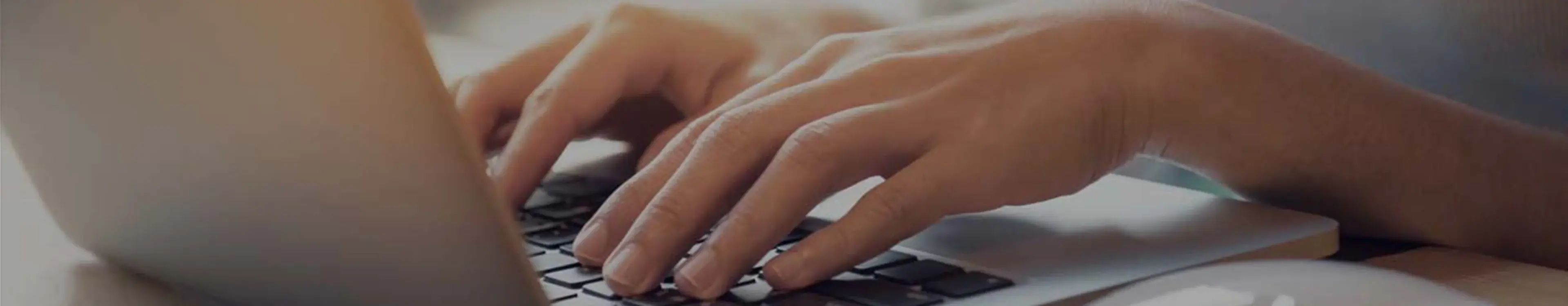 Hände tippen auf Laptop-Tastatur, Nahaufnahme in natürlichem Licht, Fokus auf Eingabeprozess