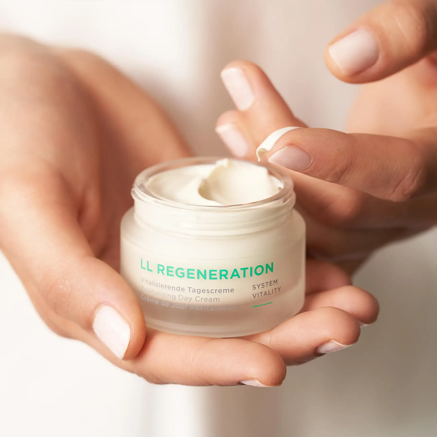 LL REGENERATION vitalisierende Tagescreme im Tiegel, Hand hält Creme und nimmt Produkt mit Finger auf