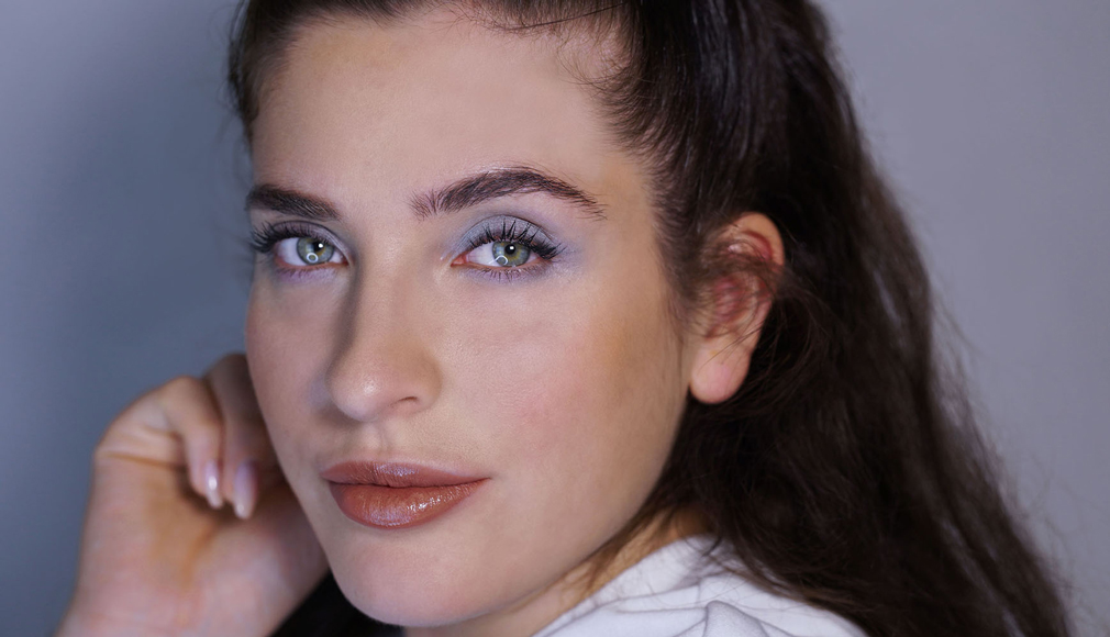 Nahaufnahme einer Frau mit blauem Lidschatten, dezentem Lippenstift und natürlichem Make-up, Blick zur Kamera