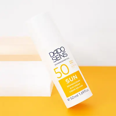 DADO SENS SUN Sonnencreme SPF 50, 50 ml, weißer Pumpflakon auf gelbem Untergrund