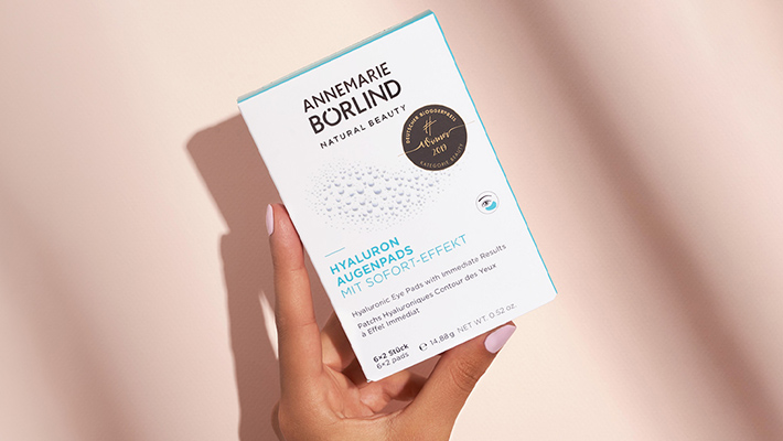 ANNEMARIE BÖRLIND Hyaluron Augenpads mit Sofort-Effekt, Verpackung in Hand vor beigem Hintergrund