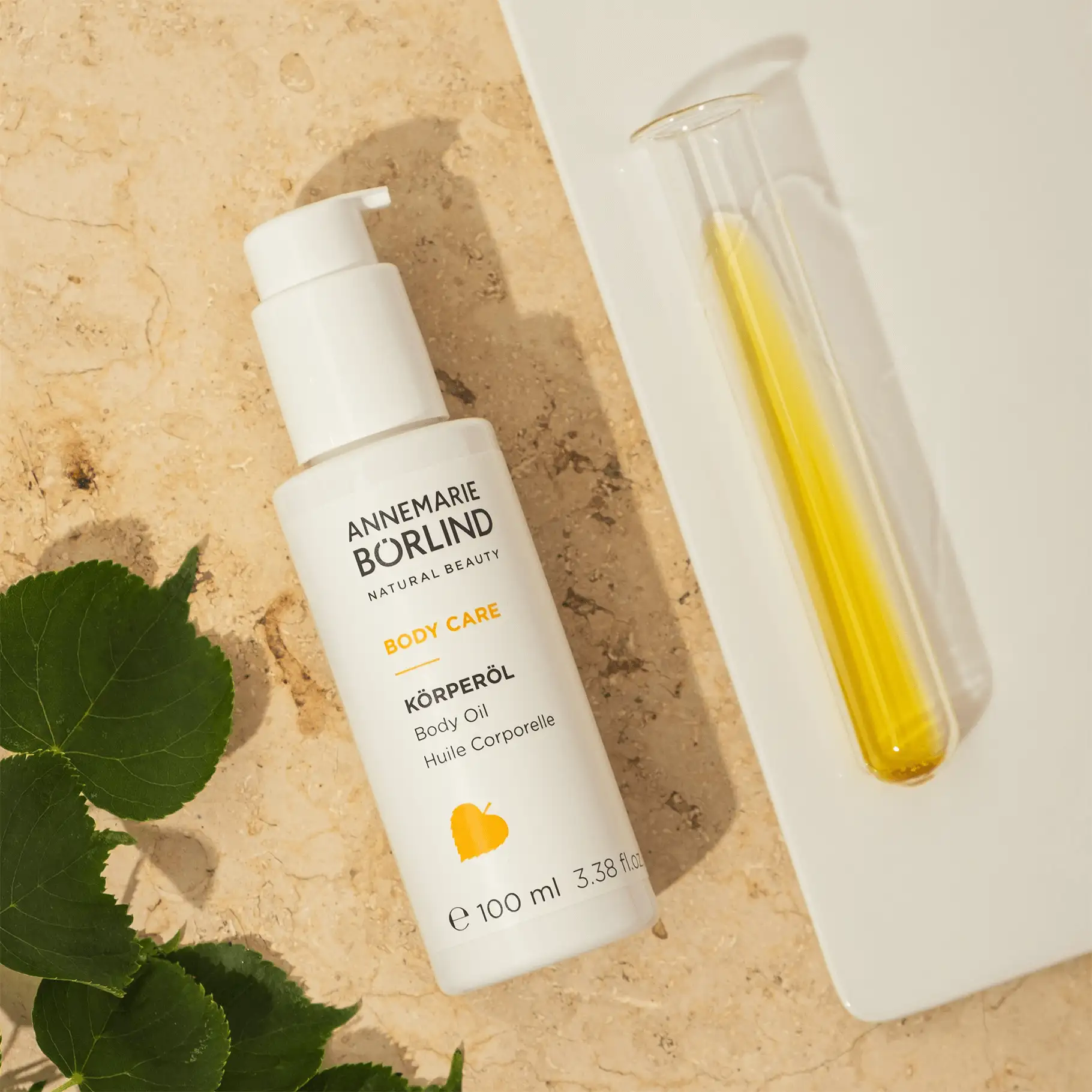 ANNEMARIE BÖRLIND BODY CARE Körperöl 100 ml mit Pumpverschluss, daneben Reagenzglas mit gelbem Öl