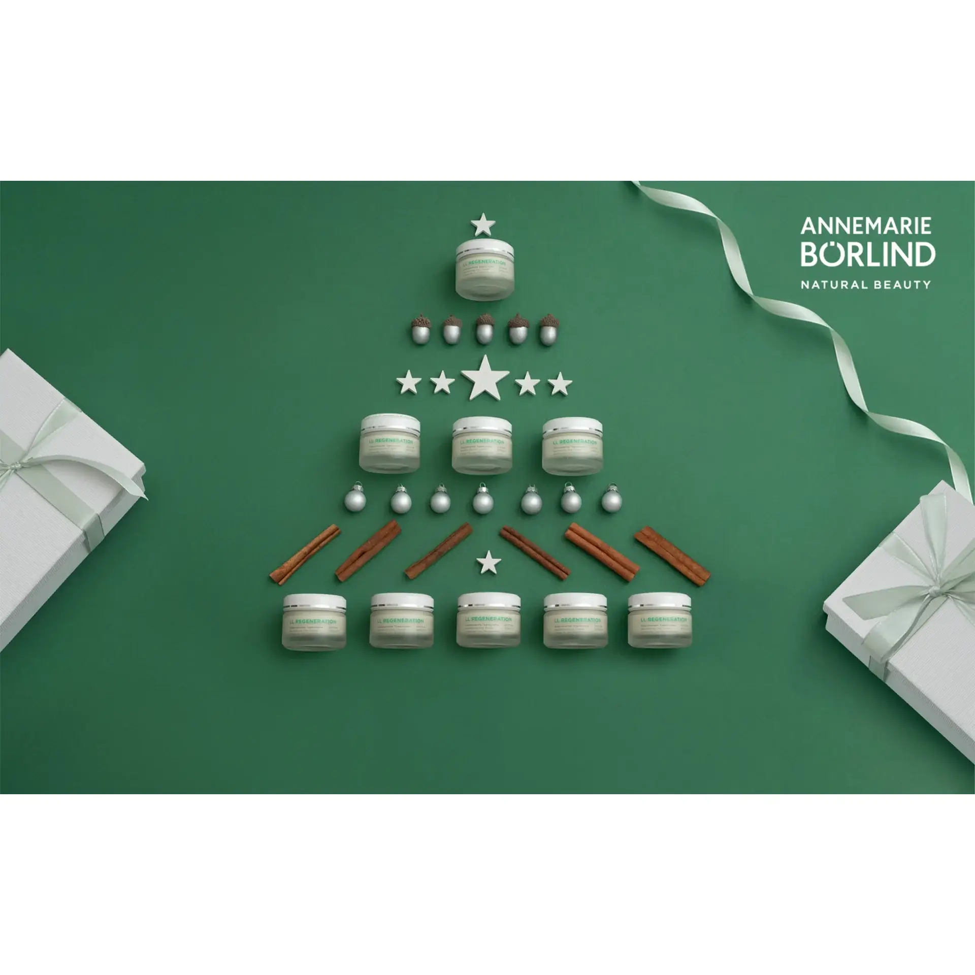 ANNEMARIE BÖRLIND Regeneration Cremetiegel als Weihnachtsbaum mit Zimtstangen, Nüssen und Geschenkboxen auf grünem Hinterg...