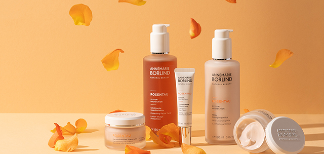 ANNEMARIE BÖRLIND ROSENTAU Gesichtspflege mit Lotion, Creme, Serum und Milde Reinigungsmilch vor orangenem Hintergrund mit...