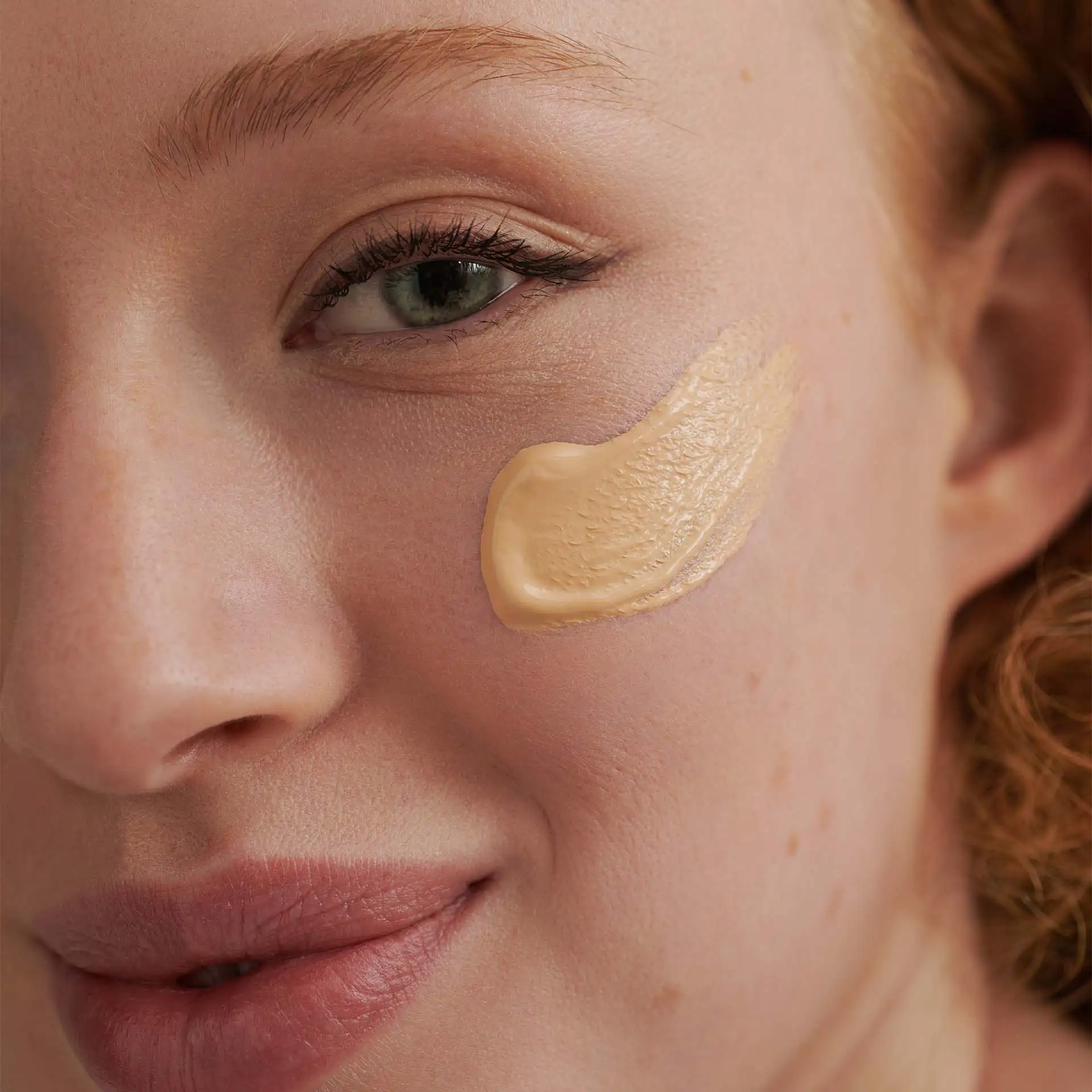 DADO SENS hypersensitive Make-up in Beige auf Wange einer Frau mit natürlichem Hautbild und leichtem Lächeln