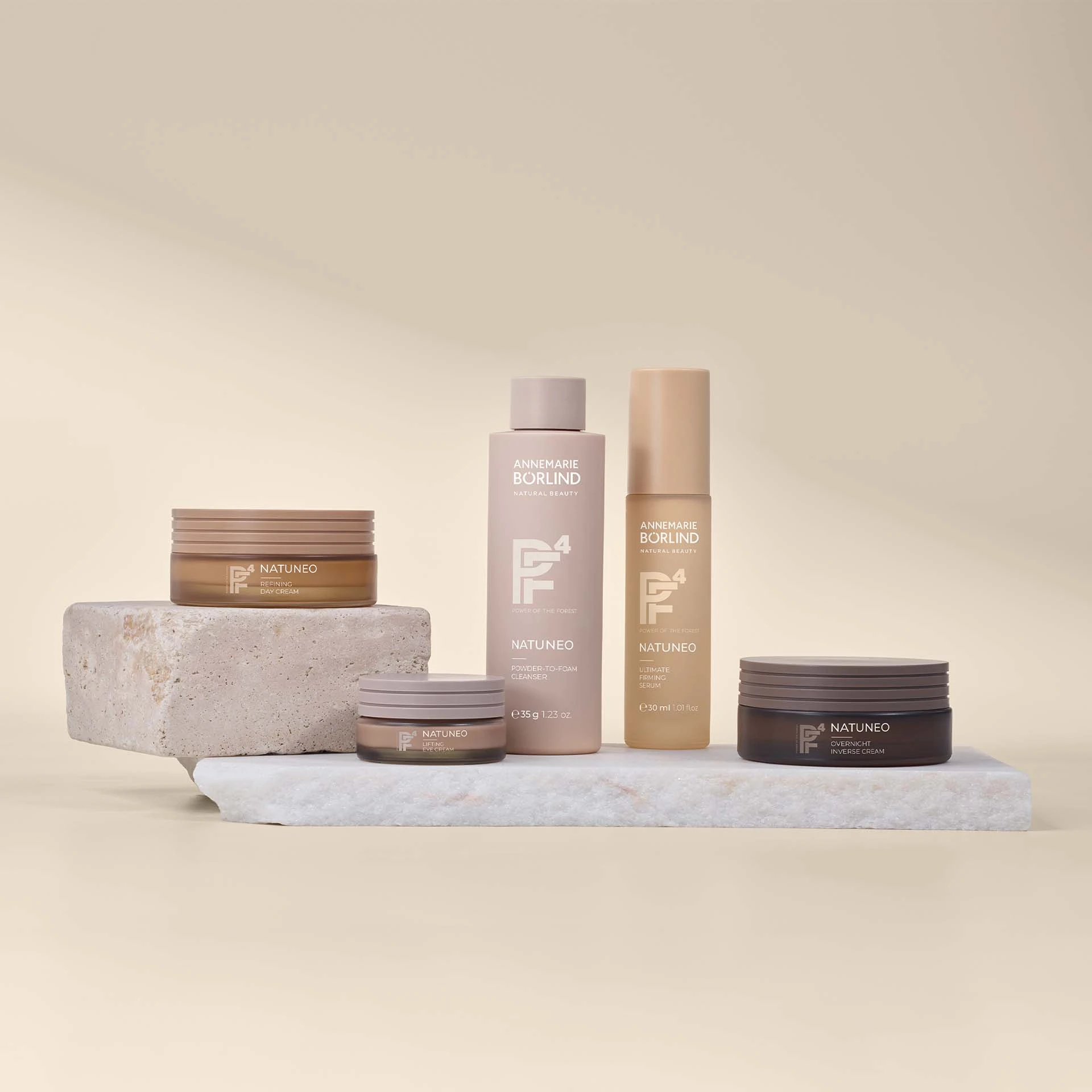 ANNEMARIE BÖRLIND NATUNEO Tagescreme, Augencreme, Cleanser, Serum und Nachtcreme auf Steinplatten arrangiert