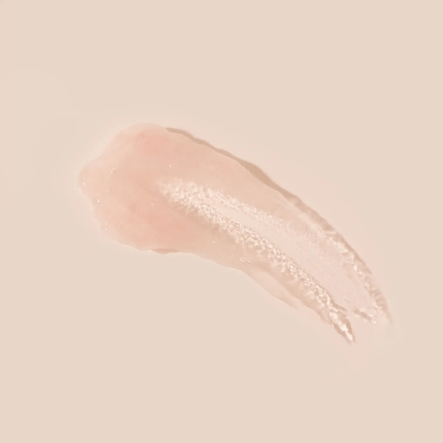 Textur eines hellrosa, cremigen Fruchtsäurepeelings mit feinen Partikeln auf beigem Hintergrund