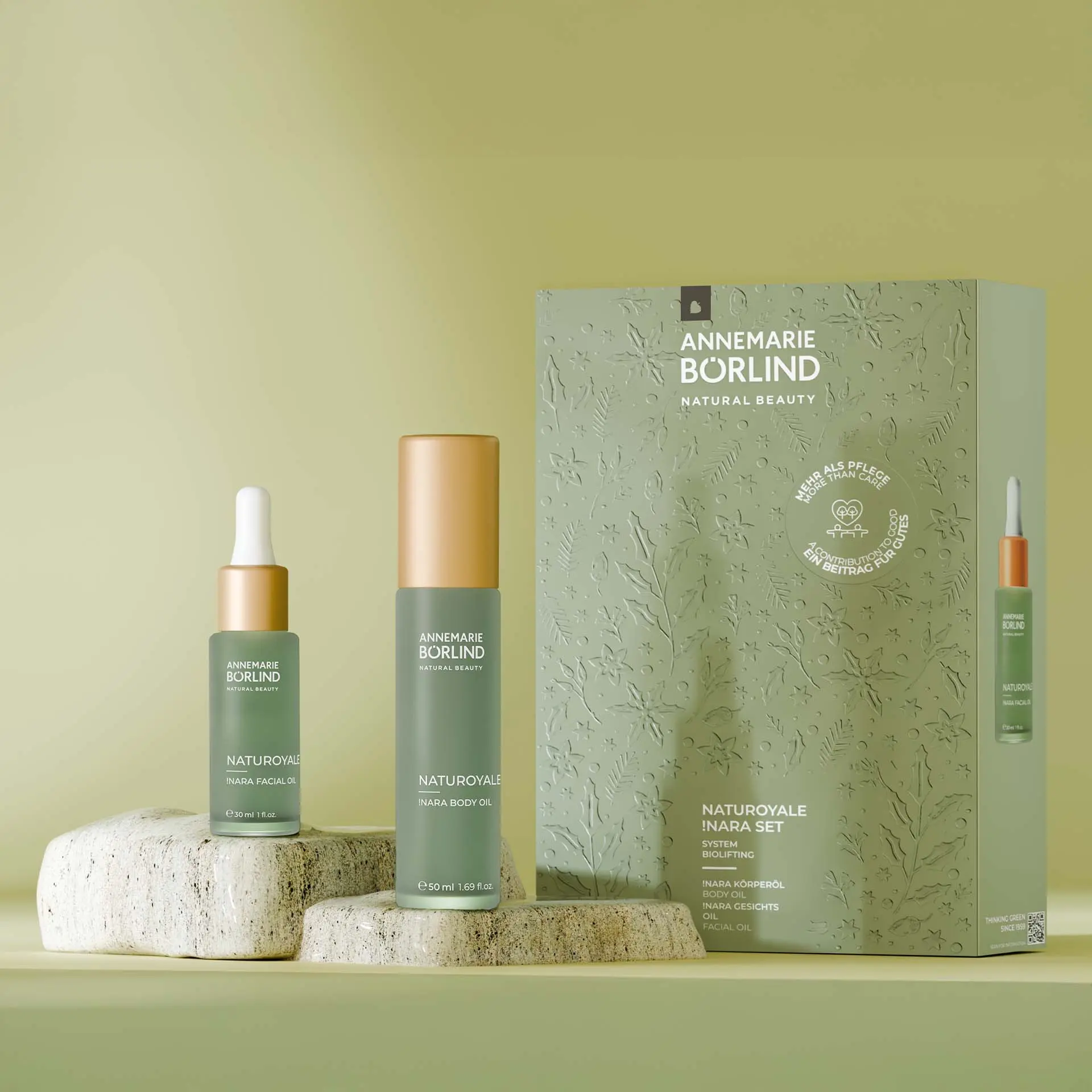 NATUROYALE Nara Facial Oil und Nara Body Oil in grüner Flasche vor Faltschachtel und neben hellem Stein abgebildet