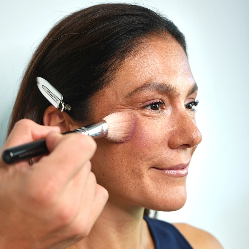 Make-up Artist Kevin Bete trägt den Blush aus dem ANNEMARIE BÖRLIND 2in1 Bronzer & Blush für den Herbst Make-up Look „A Hug of Colour“ auf die Wangen auf