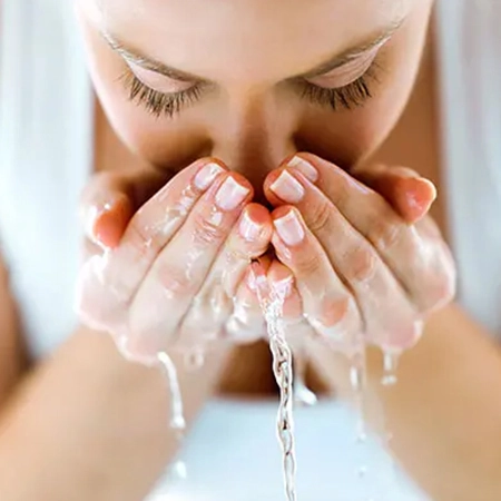 Spätakne Frau reinigt ihr Gesicht mit Wasser – symbolisch für sanfte Hautpflege bei Spätakne.