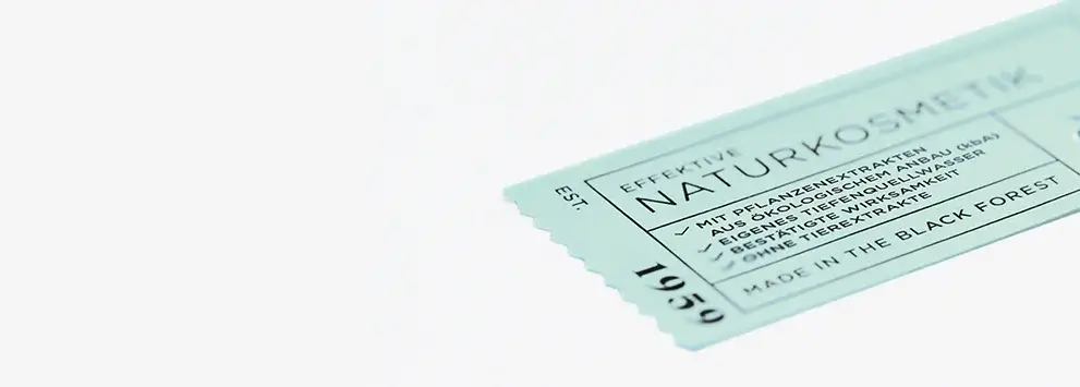 Verpackung mit Text zu Naturkosmetik, pflanzlichen Extrakten und Herstellung im Schwarzwald, hellblauer Hintergrund