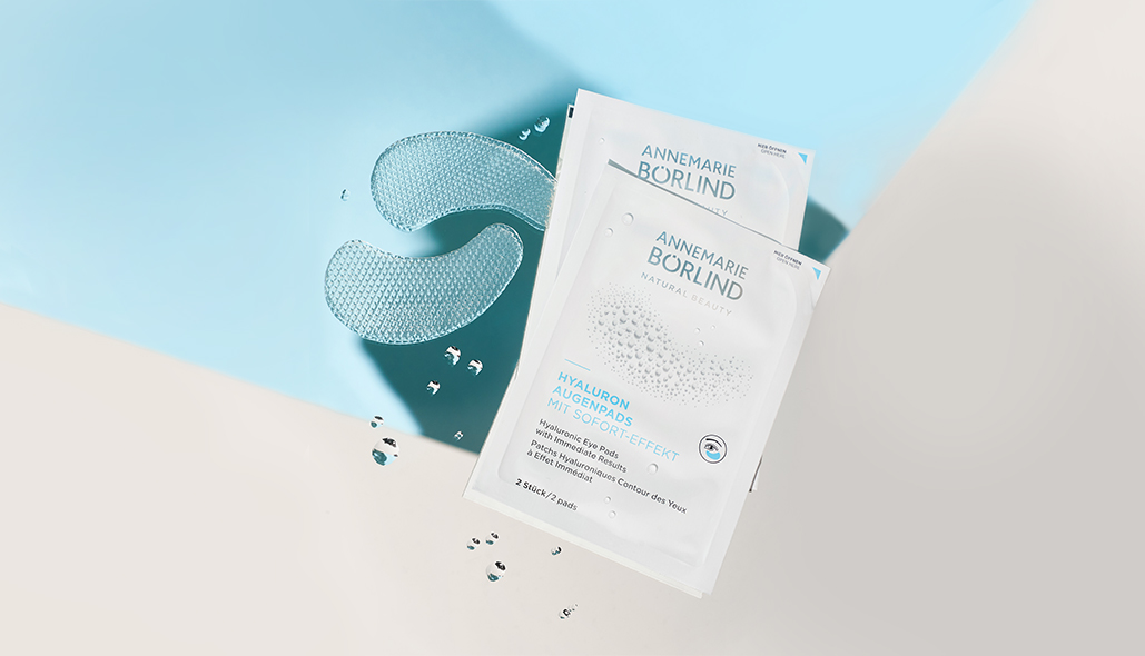 ANNEMARIE BÖRLIND Hyaluron Augenpads mit Sofort-Effekt, zwei Pads und zwei Verpackungen auf blau-beigem Hintergrund