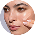 Nahaufnahme einer Frau, die eine Creme auf die Wange aufträgt, glatte Haut, natürlicher Look